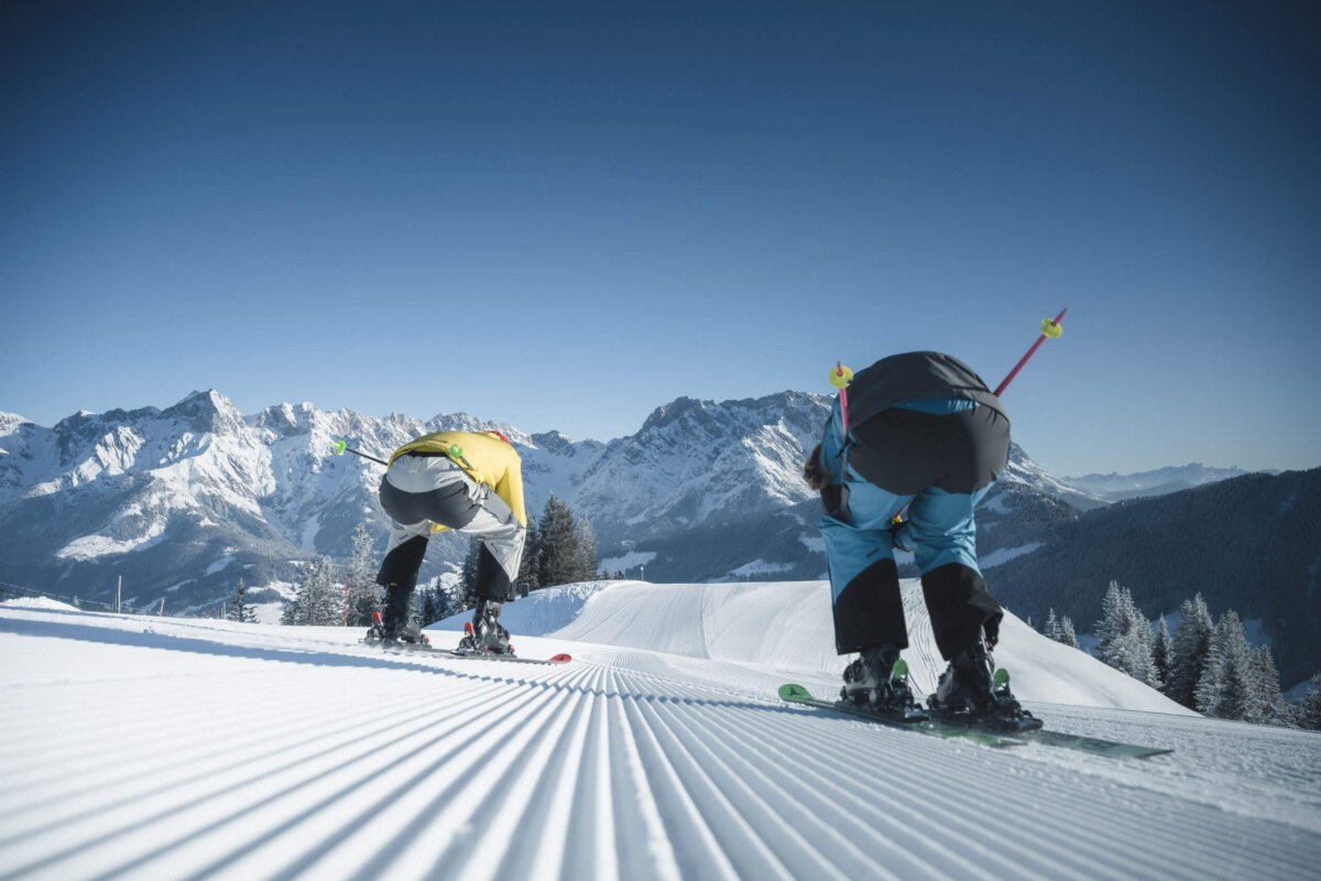 Skifahren - 2 Personen fahren die Piste runter